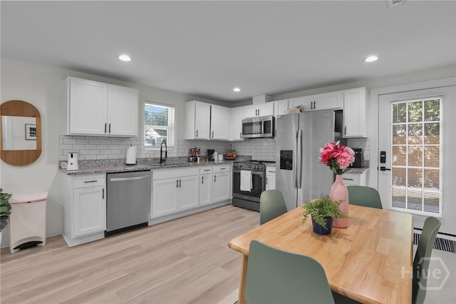 1220 E 69th St, Savannah, GA 31404 - kitchen featuring stainless steel appliances, backsplash, white cabinets, light wood-style flooring, and recessed lighting