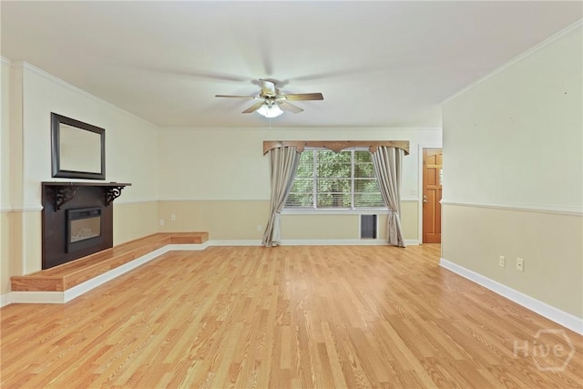 2317 Ga Highway 24, Statesboro, GA 30461 - unfurnished living room featuring crown molding, ceiling fan, a glass covered fireplace, light wood finished floors, and baseboards
