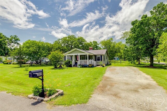 149 Spruce St, Richmond Hill, GA 31324 - view of front of house featuring covered porch, a front lawn, and asphalt driveway