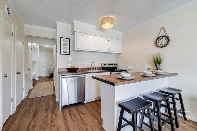 1217 Bay St Unit 105A, Tybee Island, GA 31328 - kitchen featuring stainless steel appliances, butcher block counters, a breakfast bar, white cabinets, and dark wood-style floors