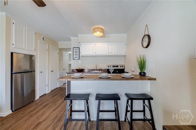 1217 Bay St Unit 105A, Tybee Island, GA 31328 - kitchen with appliances with stainless steel finishes, white cabinetry, a textured ceiling, a breakfast bar area, and a peninsula