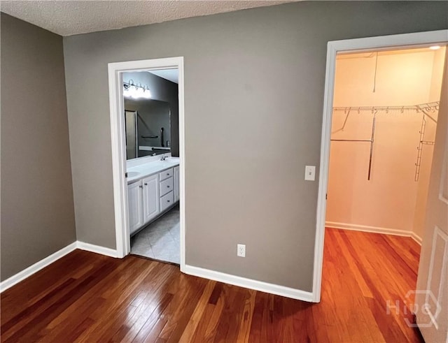 122 River Pointe Dr, Savannah, GA 31410 - unfurnished bedroom with wood finished floors, a spacious closet, a closet, a textured ceiling, and connected bathroom