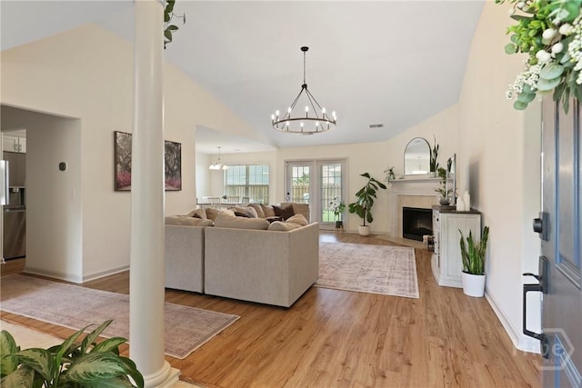 175 Willow Point Cir, Savannah, GA 31407 - living room with a chandelier, light wood-style flooring, ornate columns, a fireplace, and high vaulted ceiling