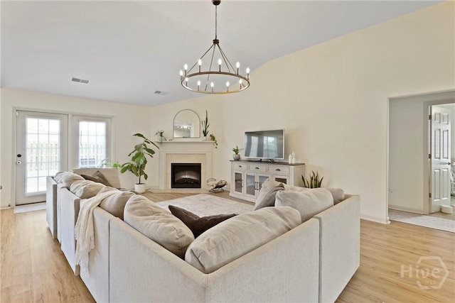 175 Willow Point Cir, Savannah, GA 31407 - living room featuring light wood-style flooring, a chandelier, vaulted ceiling, and a fireplace with flush hearth