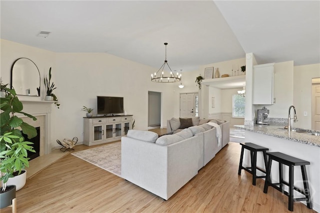175 Willow Point Cir, Savannah, GA 31407 - living area featuring a chandelier, vaulted ceiling, light wood-style floors, and a fireplace