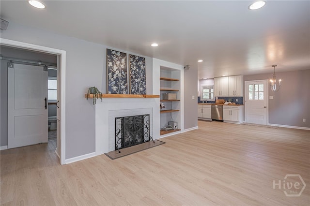 177 E Burkhalter St, Pembroke, GA 31321 - unfurnished living room featuring light wood-style flooring, a fireplace, a chandelier, recessed lighting, and a barn door