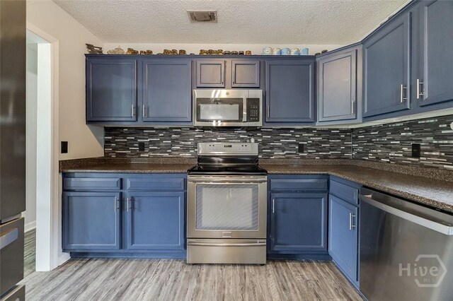 251 Old Louisville Rd, Guyton, GA 31312 - kitchen with appliances with stainless steel finishes, dark countertops, blue cabinets, light wood-style floors, and a textured ceiling