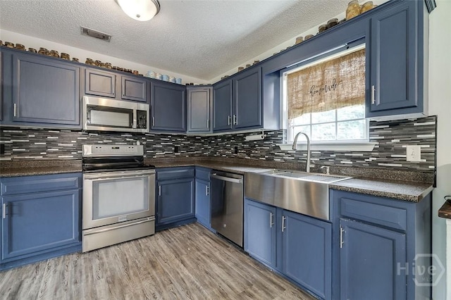 251 Old Louisville Rd, Guyton, GA 31312 - kitchen featuring stainless steel appliances, blue cabinetry, dark countertops, a textured ceiling, and decorative backsplash