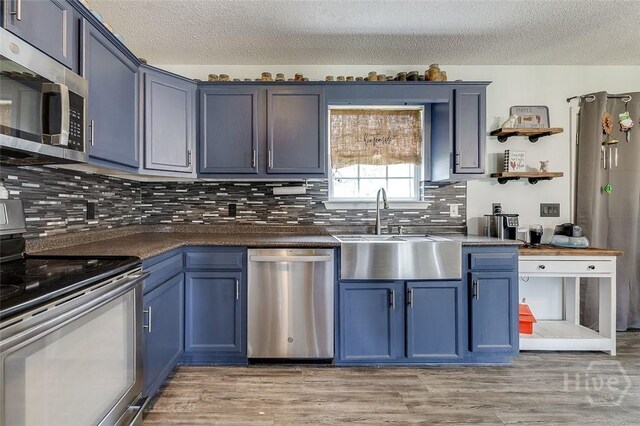 251 Old Louisville Rd, Guyton, GA 31312 - kitchen with appliances with stainless steel finishes, blue cabinetry, a textured ceiling, open shelves, and dark countertops