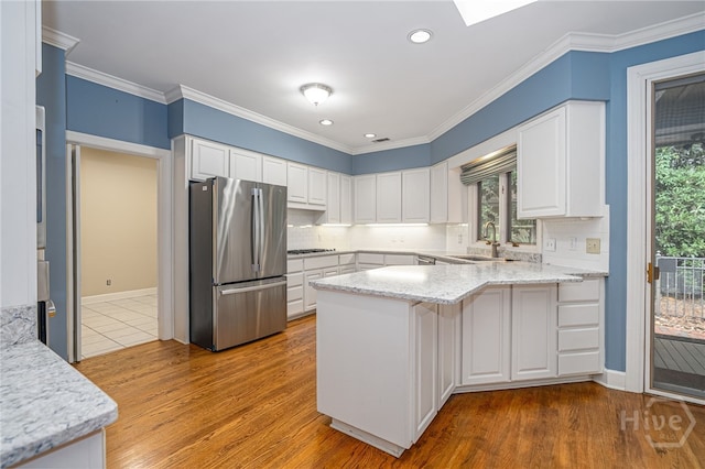 4 Hedgewood Ln, Savannah, GA 31411 - kitchen featuring freestanding refrigerator, a peninsula, backsplash, white cabinetry, and light wood finished floors