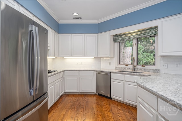 4 Hedgewood Ln, Savannah, GA 31411 - kitchen with appliances with stainless steel finishes, white cabinets, dark wood-style floors, ornamental molding, and decorative backsplash