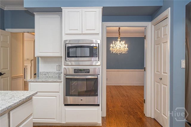 4 Hedgewood Ln, Savannah, GA 31411 - kitchen featuring stainless steel appliances, ornamental molding, a chandelier, wood finished floors, and white cabinetry