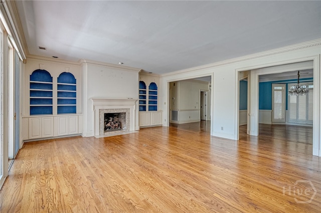 4 Hedgewood Ln, Savannah, GA 31411 - unfurnished living room with built in features, a chandelier, crown molding, a high end fireplace, and light wood-type flooring