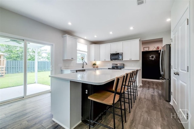 151 Excel Dr, Richmond Hill, GA 31324 - kitchen with stainless steel appliances, wood finished floors, light countertops, a breakfast bar area, and recessed lighting