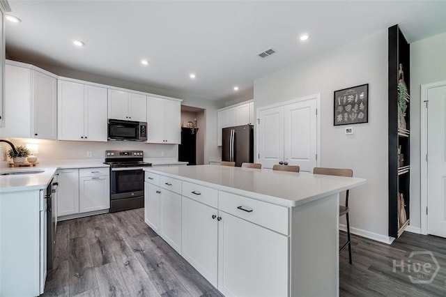 151 Excel Dr, Richmond Hill, GA 31324 - kitchen with stainless steel range with electric stovetop, freestanding refrigerator, a center island, wood finished floors, and a breakfast bar area