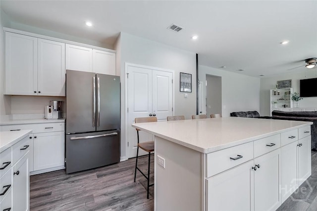 151 Excel Dr, Richmond Hill, GA 31324 - kitchen with freestanding refrigerator, a kitchen breakfast bar, wood finished floors, white cabinets, and light countertops