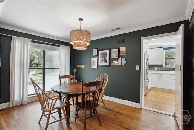 5527 Habersham St, Savannah, GA 31405 - dining space featuring healthy amount of natural light, light wood-style flooring, a chandelier, and crown molding
