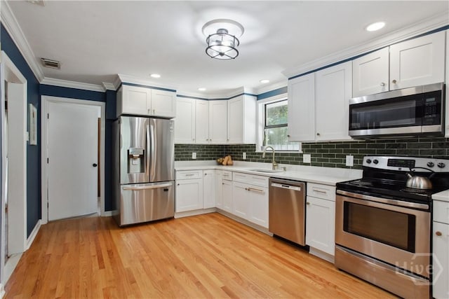 5527 Habersham St, Savannah, GA 31405 - kitchen featuring appliances with stainless steel finishes, crown molding, light countertops, backsplash, and light wood finished floors