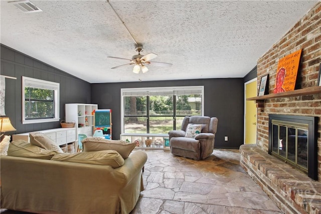 5527 Habersham St, Savannah, GA 31405 - living area featuring stone flooring, ceiling fan, a fireplace, vaulted ceiling, and a textured ceiling