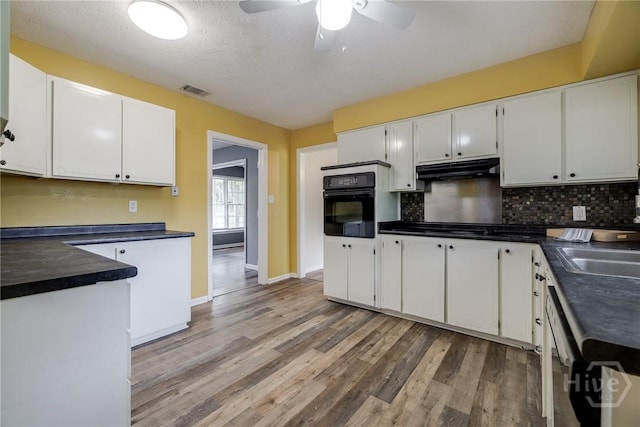 41 Barrington Cir, Savannah, GA 31419 - kitchen with black oven, under cabinet range hood, dark countertops, light wood-type flooring, and a ceiling fan