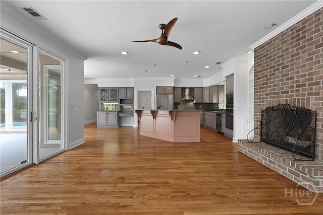 8 Boars Nest Ln, Savannah, GA 31411 - kitchen with wall chimney range hood, stainless steel appliances, ornamental molding, a kitchen breakfast bar, and gray cabinetry