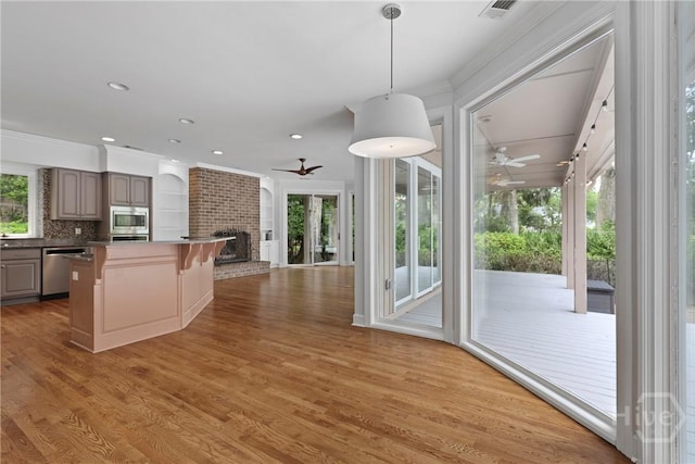 8 Boars Nest Ln, Savannah, GA 31411 - kitchen featuring ceiling fan, appliances with stainless steel finishes, open floor plan, a breakfast bar area, and ornamental molding
