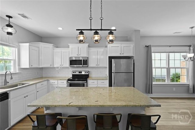 623 E Henry St, Savannah, GA 31401 - kitchen with appliances with stainless steel finishes, a center island, white cabinets, tasteful backsplash, and recessed lighting