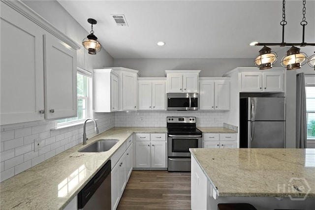 623 E Henry St, Savannah, GA 31401 - kitchen featuring stainless steel appliances, white cabinets, light stone countertops, dark wood-style flooring, and hanging light fixtures
