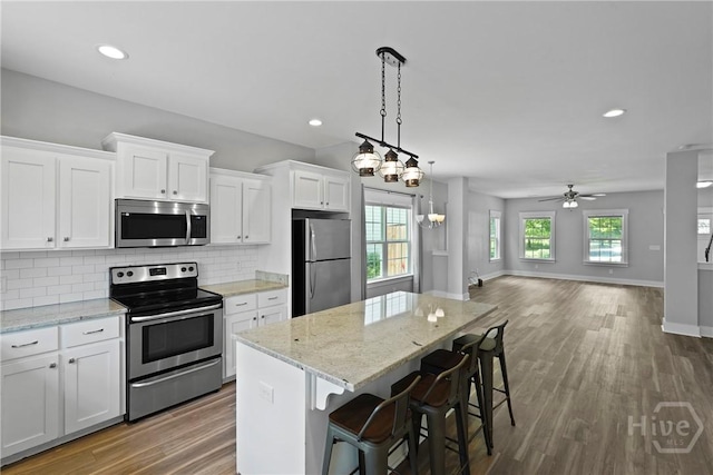623 E Henry St, Savannah, GA 31401 - kitchen with stainless steel appliances, open floor plan, white cabinets, a kitchen island, and decorative backsplash