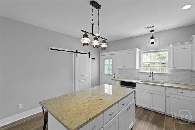623 E Henry St, Savannah, GA 31401 - kitchen with dishwasher, a barn door, decorative backsplash, white cabinetry, and recessed lighting