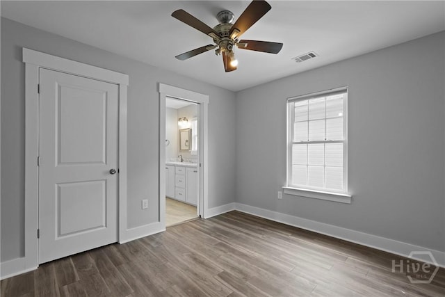 623 E Henry St, Savannah, GA 31401 - unfurnished bedroom with wood finished floors, connected bathroom, and ceiling fan
