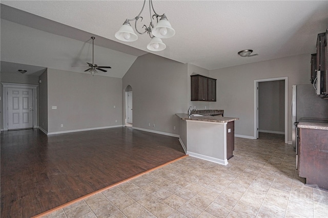 1506 Bayberry Dr, Hinesville, GA 31313 - kitchen with arched walkways, dark brown cabinetry, ceiling fan, lofted ceiling, and freestanding refrigerator