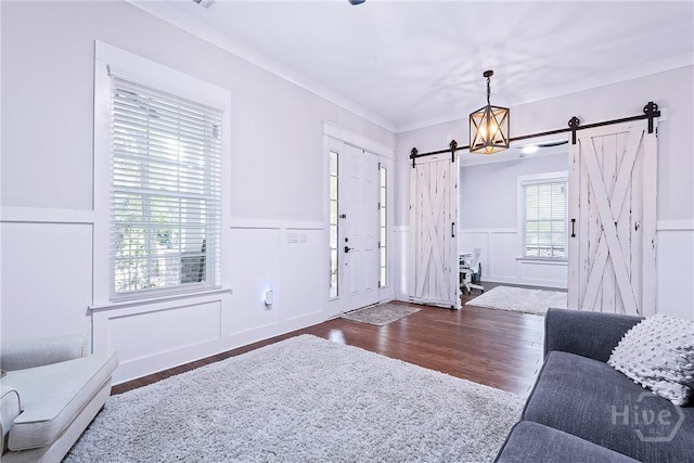 370 Blackjack Oak Dr W, Richmond Hill, GA 31324 - living area with a barn door, a decorative wall, wood finished floors, a wainscoted wall, and ornamental molding