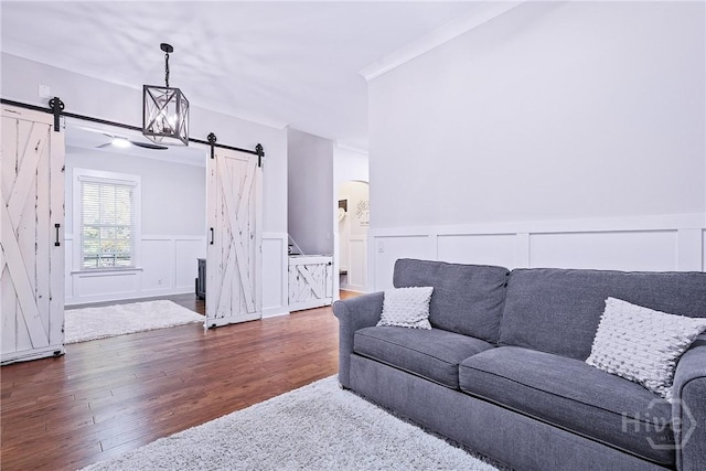 370 Blackjack Oak Dr W, Richmond Hill, GA 31324 - living area featuring a barn door, a decorative wall, wood finished floors, a wainscoted wall, and arched walkways