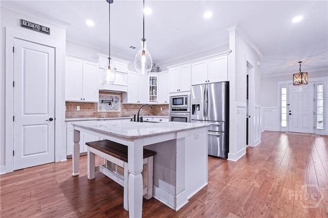 370 Blackjack Oak Dr W, Richmond Hill, GA 31324 - kitchen featuring appliances with stainless steel finishes, glass insert cabinets, white cabinetry, an island with sink, and recessed lighting
