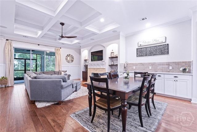 370 Blackjack Oak Dr W, Richmond Hill, GA 31324 - dining space with a fireplace, a ceiling fan, light wood-style flooring, beam ceiling, and coffered ceiling