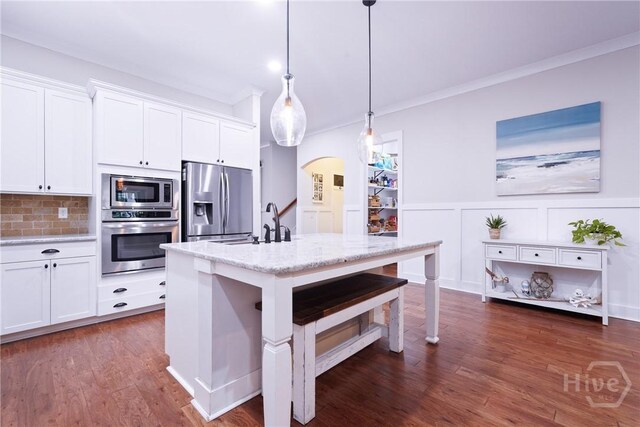 370 Blackjack Oak Dr W, Richmond Hill, GA 31324 - kitchen with stainless steel appliances, arched walkways, white cabinets, light stone countertops, and a breakfast bar
