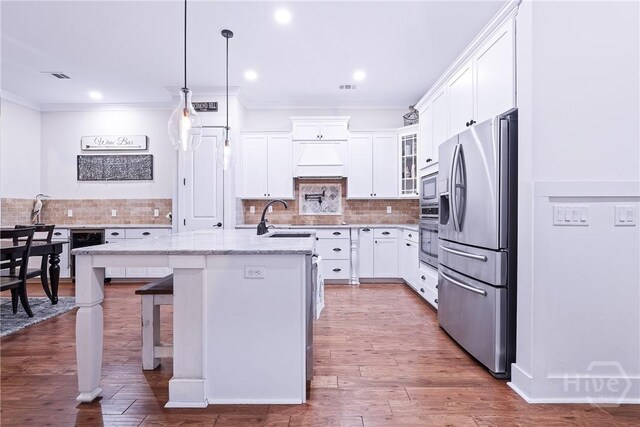 370 Blackjack Oak Dr W, Richmond Hill, GA 31324 - kitchen featuring appliances with stainless steel finishes, a center island with sink, white cabinetry, backsplash, and ornamental molding
