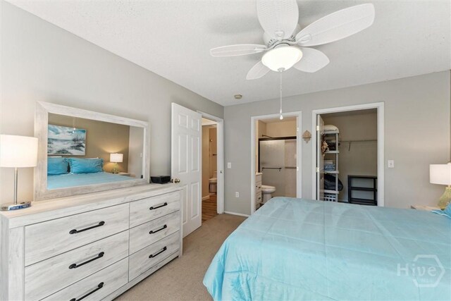 12300 Apache Ave Unit 1003, Savannah, GA 31419 - bedroom with light colored carpet, ensuite bathroom, a walk in closet, and a ceiling fan
