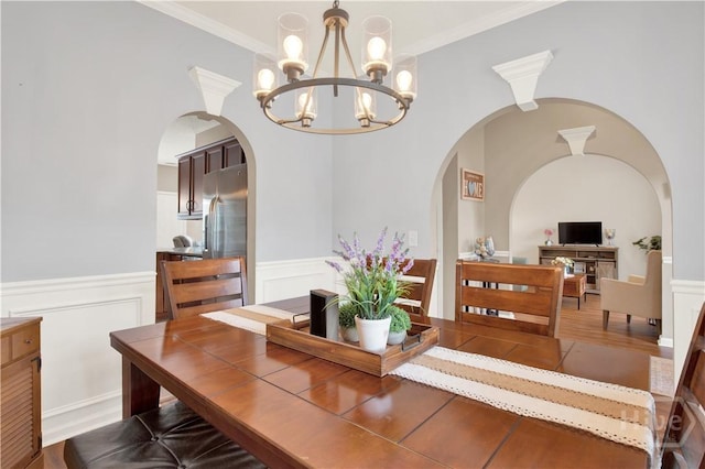306 Walthour Dr, Rincon, GA 31326 - dining room featuring arched walkways, a chandelier, wainscoting, wood finished floors, and ornamental molding