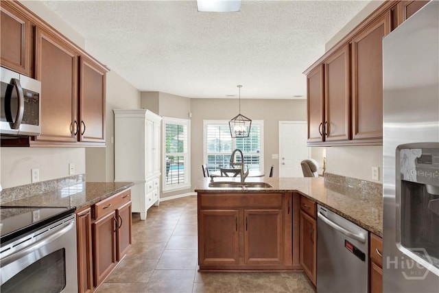 306 Walthour Dr, Rincon, GA 31326 - kitchen featuring stainless steel appliances, a peninsula, brown cabinetry, dark stone counters, and a textured ceiling