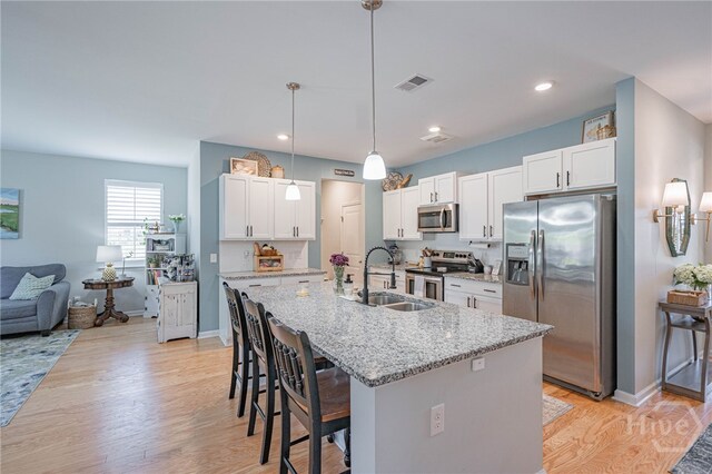 143 Arusha Ave, Savannah, GA 31419 - kitchen featuring appliances with stainless steel finishes, a breakfast bar, white cabinetry, light wood-style flooring, and recessed lighting