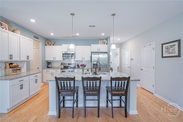 143 Arusha Ave, Savannah, GA 31419 - kitchen featuring stainless steel appliances, light wood-style floors, white cabinetry, a breakfast bar, and decorative light fixtures