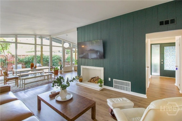 320 Windsor Rd, Savannah, GA 31419 - living room with wood finished floors, a wall of windows, wood walls, and a fireplace with raised hearth