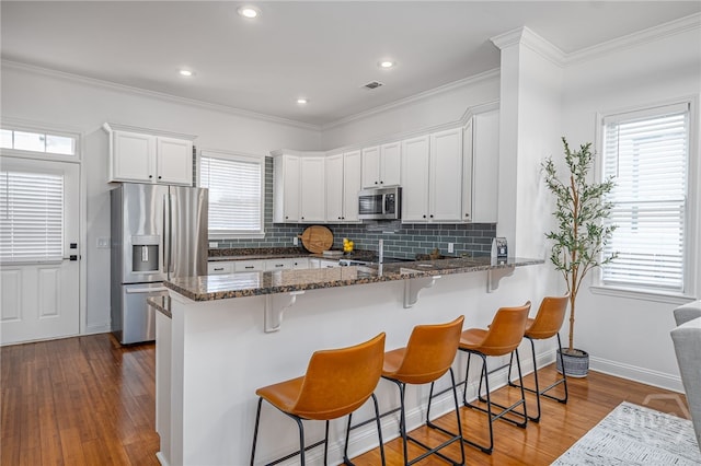 316 E 31st St, Savannah, GA 31401 - kitchen featuring appliances with stainless steel finishes, tasteful backsplash, dark stone counters, white cabinets, and wood finished floors