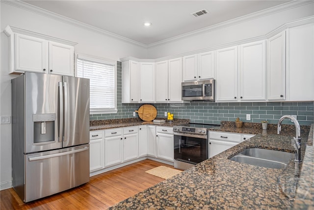316 E 31st St, Savannah, GA 31401 - kitchen with appliances with stainless steel finishes, light wood-style floors, white cabinets, ornamental molding, and backsplash