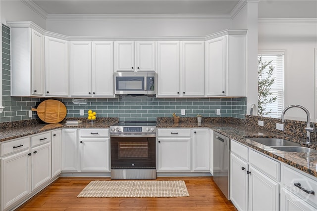 316 E 31st St, Savannah, GA 31401 - kitchen featuring appliances with stainless steel finishes, white cabinets, ornamental molding, light wood-style floors, and dark stone countertops