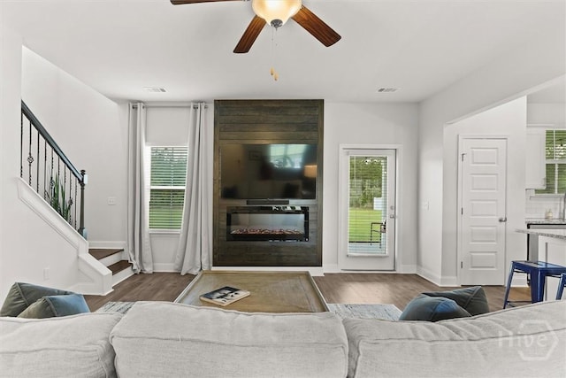 104 Finch Ln, Guyton, GA 31312 - living room featuring a large fireplace, wood finished floors, stairway, and ceiling fan
