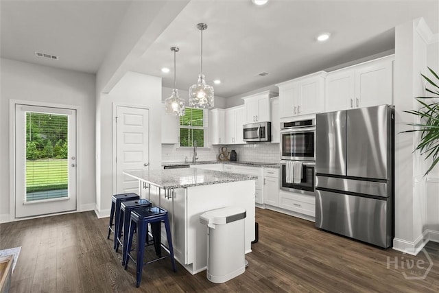 104 Finch Ln, Guyton, GA 31312 - kitchen featuring appliances with stainless steel finishes, decorative backsplash, a kitchen island, white cabinets, and light stone counters