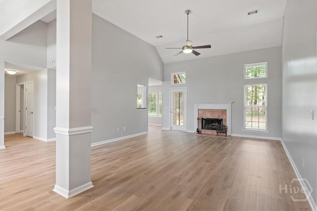 65 Golden Gate Dr, Pooler, GA 31322 - unfurnished living room with high vaulted ceiling, a ceiling fan, light wood finished floors, a tiled fireplace, and ornate columns